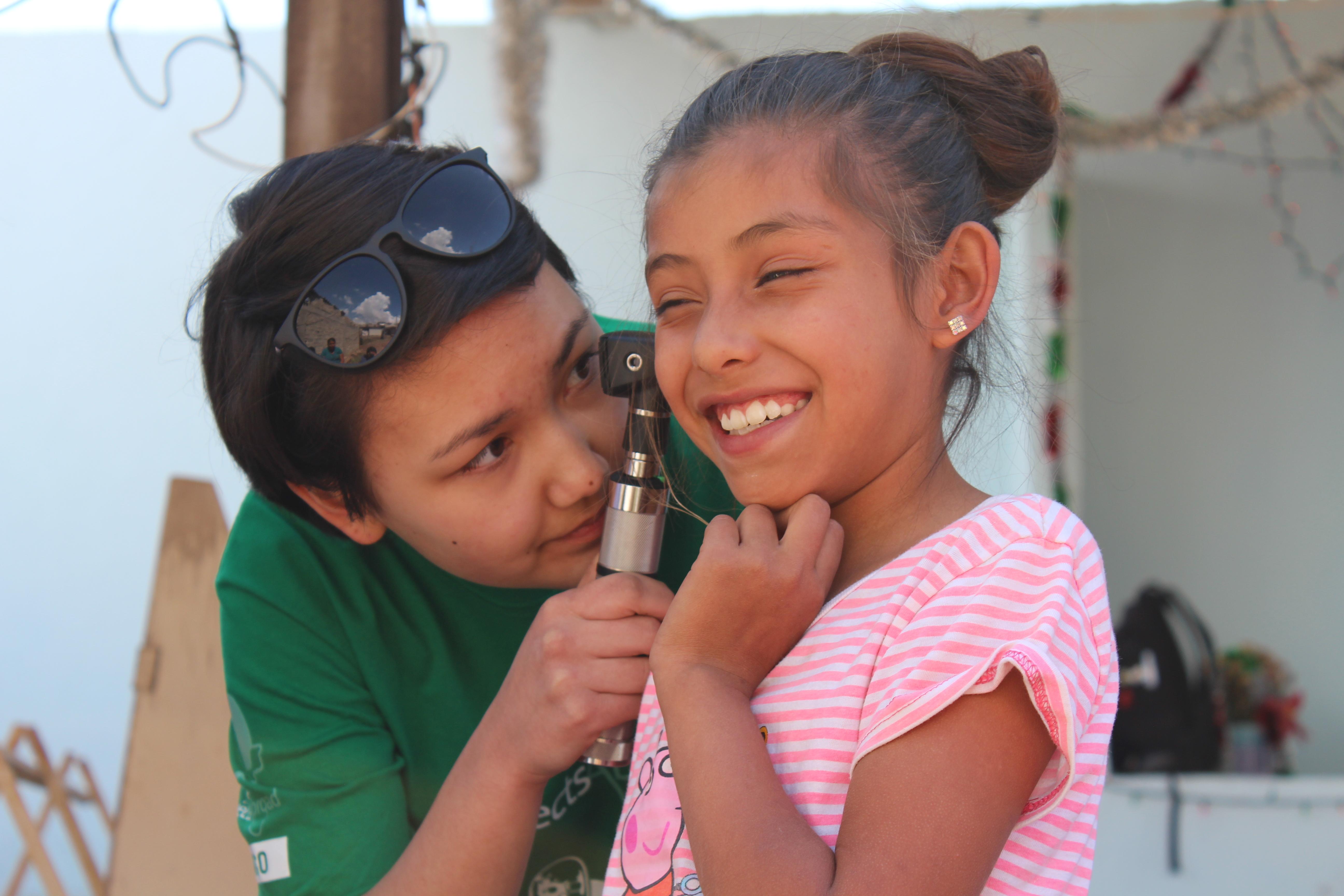 Female Medical Projects Abroad Intern examines a childs ear at a Medical Outreach during Medical internships in Mexico. Medical Intern examines a young patients ear during a Medical Community Outreach Day in Mexico.